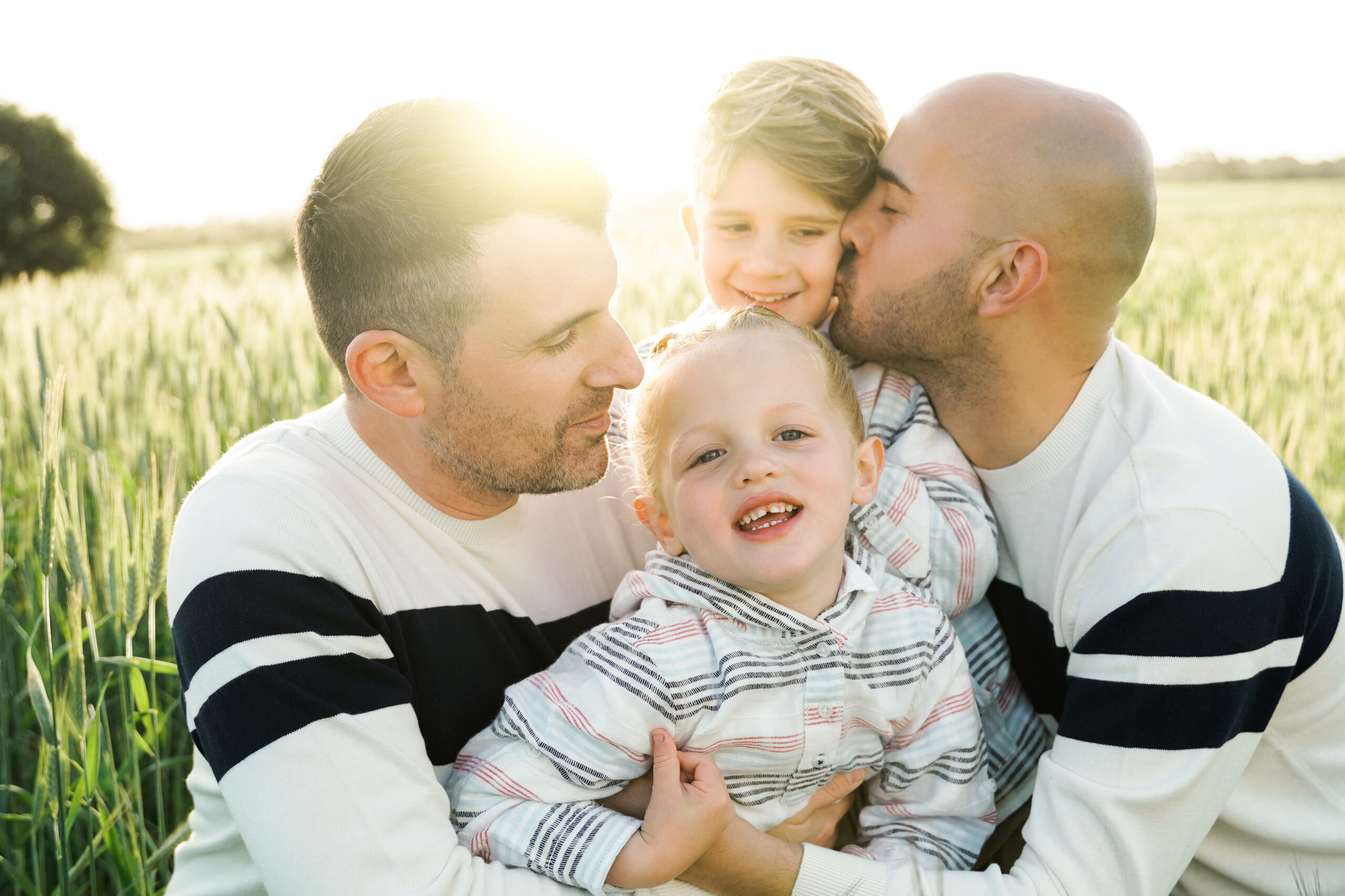 Lgbtq family: Gay couple fathers having fun with children outdoor with sunset background – Diversity love concept – Soft focus on center son face